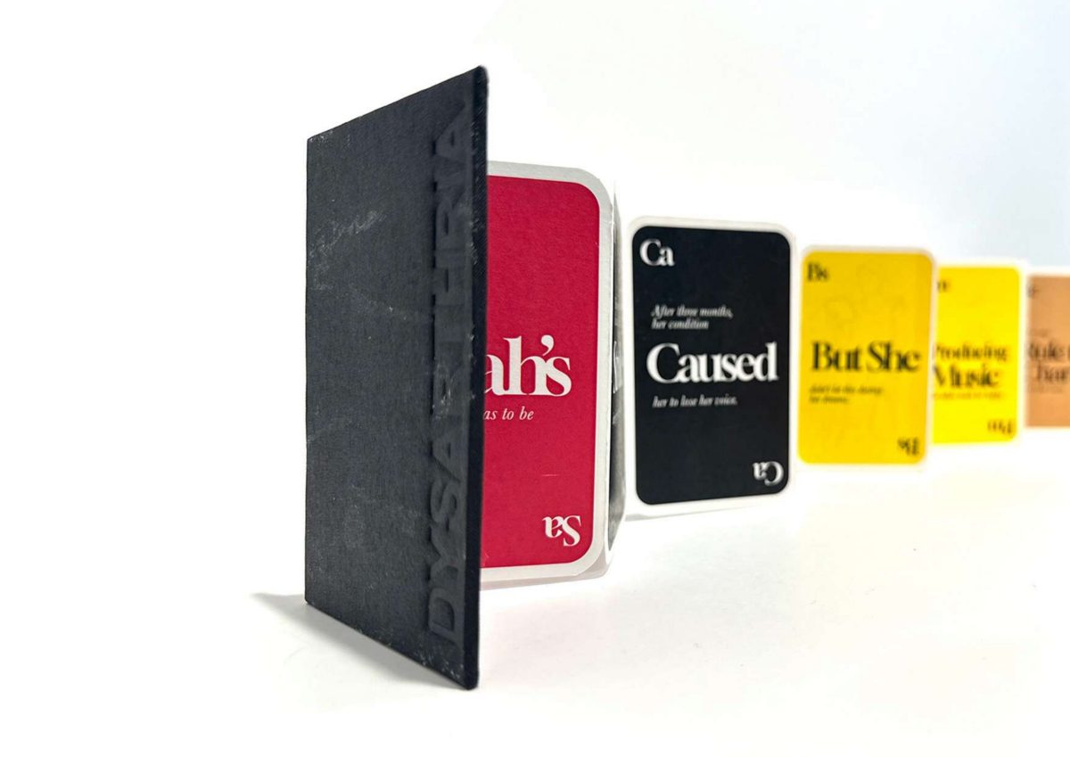 A black fabric-covered concertina book embossed with the word Dysarthria, opening onto a row of red, black and yellow story cards.